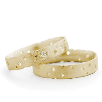 A patterned 18ct gold engagement ring with nibbled design and Radiant brilliant cut diamonds, with a frosted finish and burnished edges.