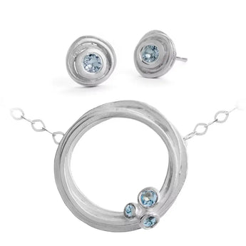 A set of silver jewelry featuring aquamarine stones, including a swirl pendant necklace and matching earrings.