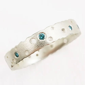 A 9ct white gold eternity ring with a frosted finish and blue diamond accents