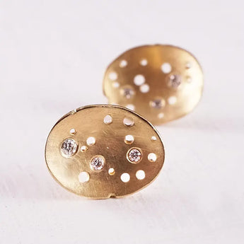 A pair of domed 18ct gold earrings with patterned surfaces and three brilliant cut diamonds set within the design.