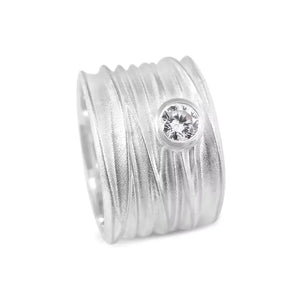 An extra wide silver ring with a textured band and a central solitaire diamond, part of the Dune Collection.