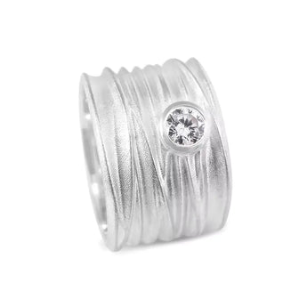 An extra wide silver ring with a textured band and a central solitaire diamond, part of the Dune Collection.