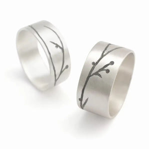 Two silver rings with hand engraved floral patterning, displayed against a white background