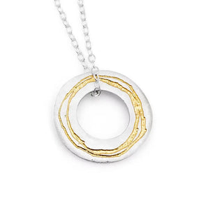 A sterling silver necklace with a gold detailed etched pendant, moving freely on a silver trace chain.