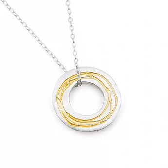 A sterling silver necklace with a gold etched pendant, featuring a hand-drawn pattern in relief, moved freely on a silver trace chain with a bolt ring catch.