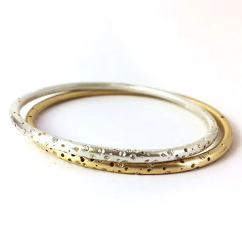 A set of two bangles, one with a gold band and the other with a silver band, both featuring scattered diamond accents and a textured pattern.