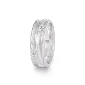 A silver ring with a textured finish and scattered diamonds set on an angle, showing the inside of the ring which is polished and smooth.