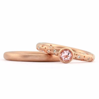 A rose gold engagement ring featuring a blush pink morganite center stone with smaller sparkling diamonds set on the band, shown alongside a plain band.