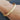 A textured gold bangle bracelet with a frosted finish worn on a person's wrist.