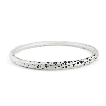 A sterling silver round bangle with a pattern of tiny holes that have been oxidised to create contrast, displayed against a white background.