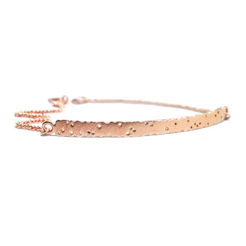 A patterned rose gold bar bracelet with a satin finish and a small chain detail at one end.
