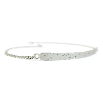 A silver bracelet featuring a diamond-patterned bar centerpiece with a loop closure, displayed against a white background.