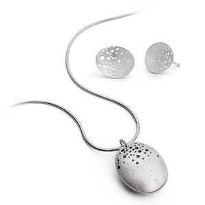 A silver necklace with a hand-drilled hollow pod pendant accompanied by a pair of dome earrings, displayed against a white background.