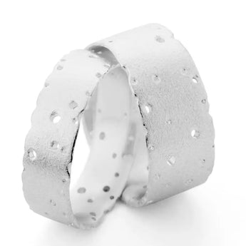 A silver-colored metal wedding ring with a frosted finish and nibbled, textured pattern.