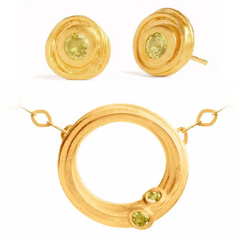 A set of gold-plated sterling silver jewelry, including a swirl design necklace with a central pendant and matching earrings, both featuring green peridot stones.