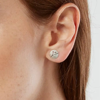 A close-up image of a woman's ear wearing a silver floral patterned earring.