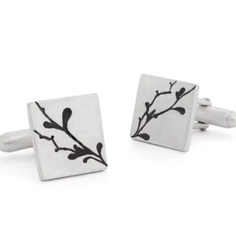A pair of silver cufflinks with engraved floral details and a satin finish.