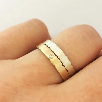 A close-up image of a person's hand showcasing a sterling silver ring with nibbled edges on the finger.