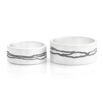 Two silver rings with etched oxidised detail, one larger and one smaller, set against a white background.