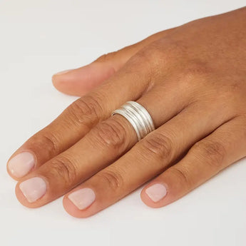 A silver ring with a textured exterior worn on a person's finger.