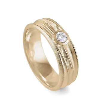 A gold solitaire diamond ring with a textured band, featuring a central round brilliant cut diamond