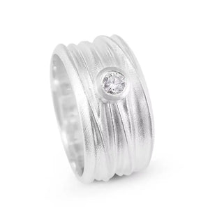 A silver diamond solitaire ring with a textured band and a single brilliant cut diamond stone set in the center.