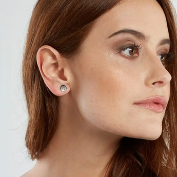A pair of silver-colored earrings with a spiral pattern and multiple holes arranged in a dome shape, displayed against a white background.