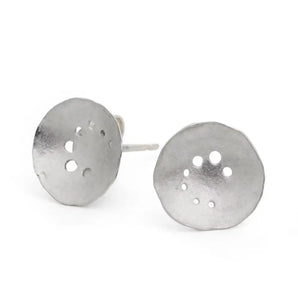 A pair of silver earrings with a spiral pattern, showing a satin finish and precision drilling, displayed against a white background.