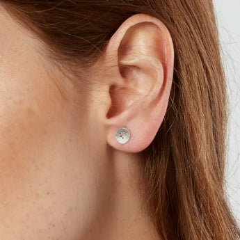 A pair of silver earrings with a spiral pattern, showing a satin finish and precision drilling, displayed against a white background.