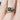 Gold ring with a green gemstone and diamond accents on a finger.