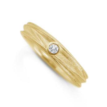 Handmade 18ct yellow gold textured ring with a slim organic band and a small round solitaire diamond set flush into the surface.