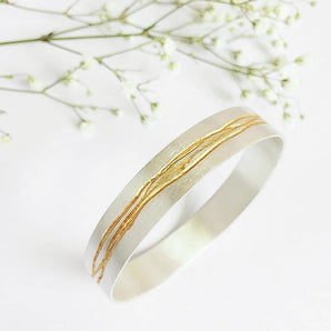 Gold and silver bangle on a white background with delicate flowers