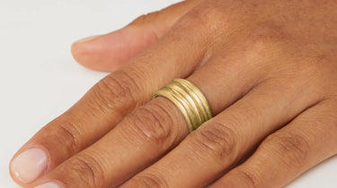 Gold ring on a person's finger against a white background