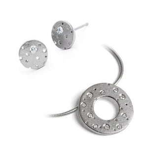 A silver necklace with a diamond-encrusted circular pendant and a pair of matching earrings, both with a frosted finish.