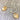 A pair of hoop earrings with gold-colored drops on silver-colored hooks, featuring a pattern of holes arranged in a circular design.