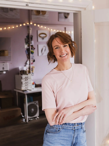 Person standing in a room with decorative lights and a desk in the background