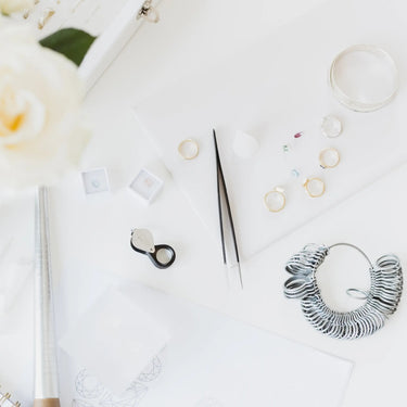 White rose, notebook, pen, and jewelry on a white surface