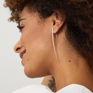 A side profile of a woman wearing long silver strand earrings with a satin finish.