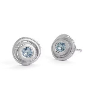 A pair of silver swirl earrings with central aquamarine stones, set against a white background.