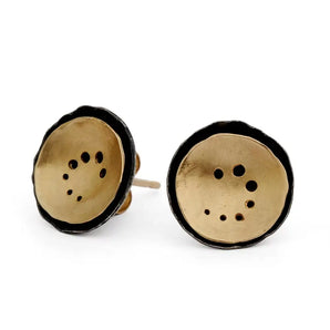 A pair of silver and gold round layered earrings with a domed design and multiple patterned holes