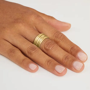 A wide, textured yellow gold wedding ring on a person's finger, showcasing its design and fit.